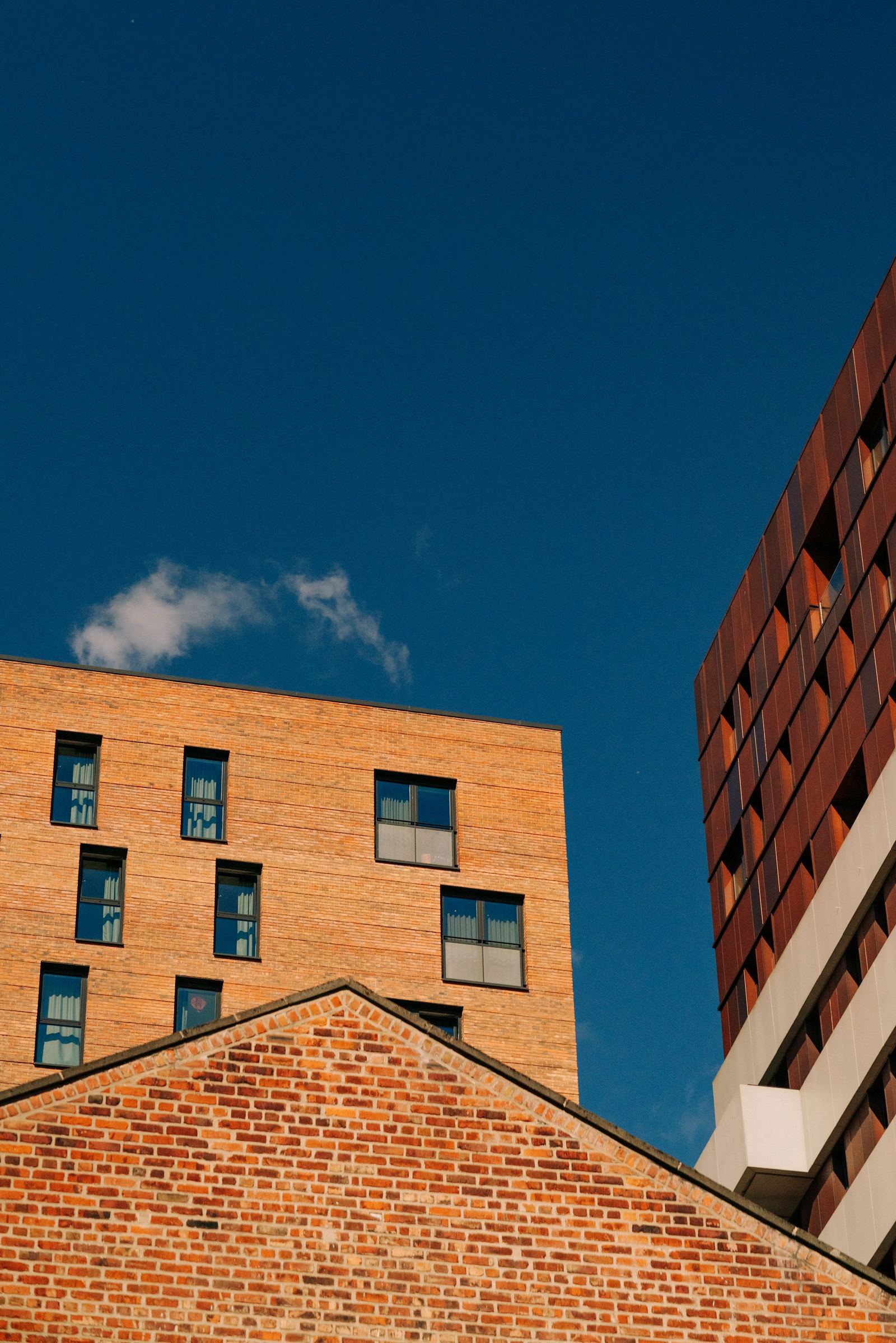 Brick apartment buildings and a pitched roof against a deep blue sky