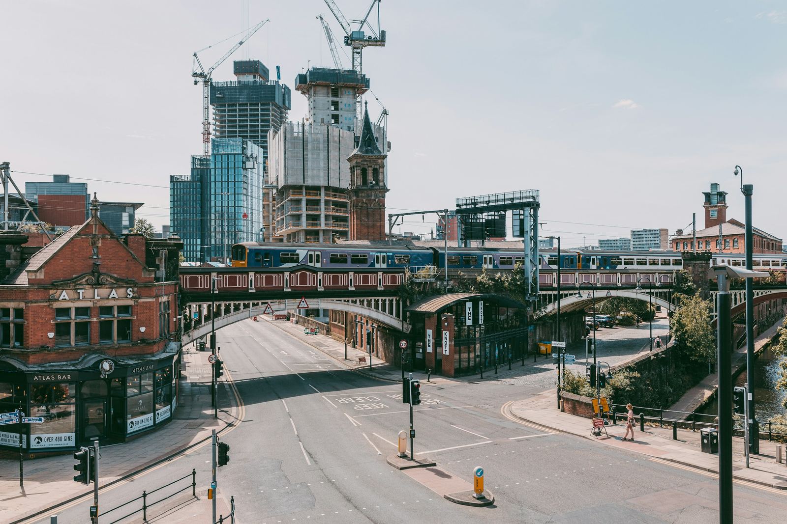 A train crossing the railway viaduct over Deansgate, with towers under construction and their cranes behind