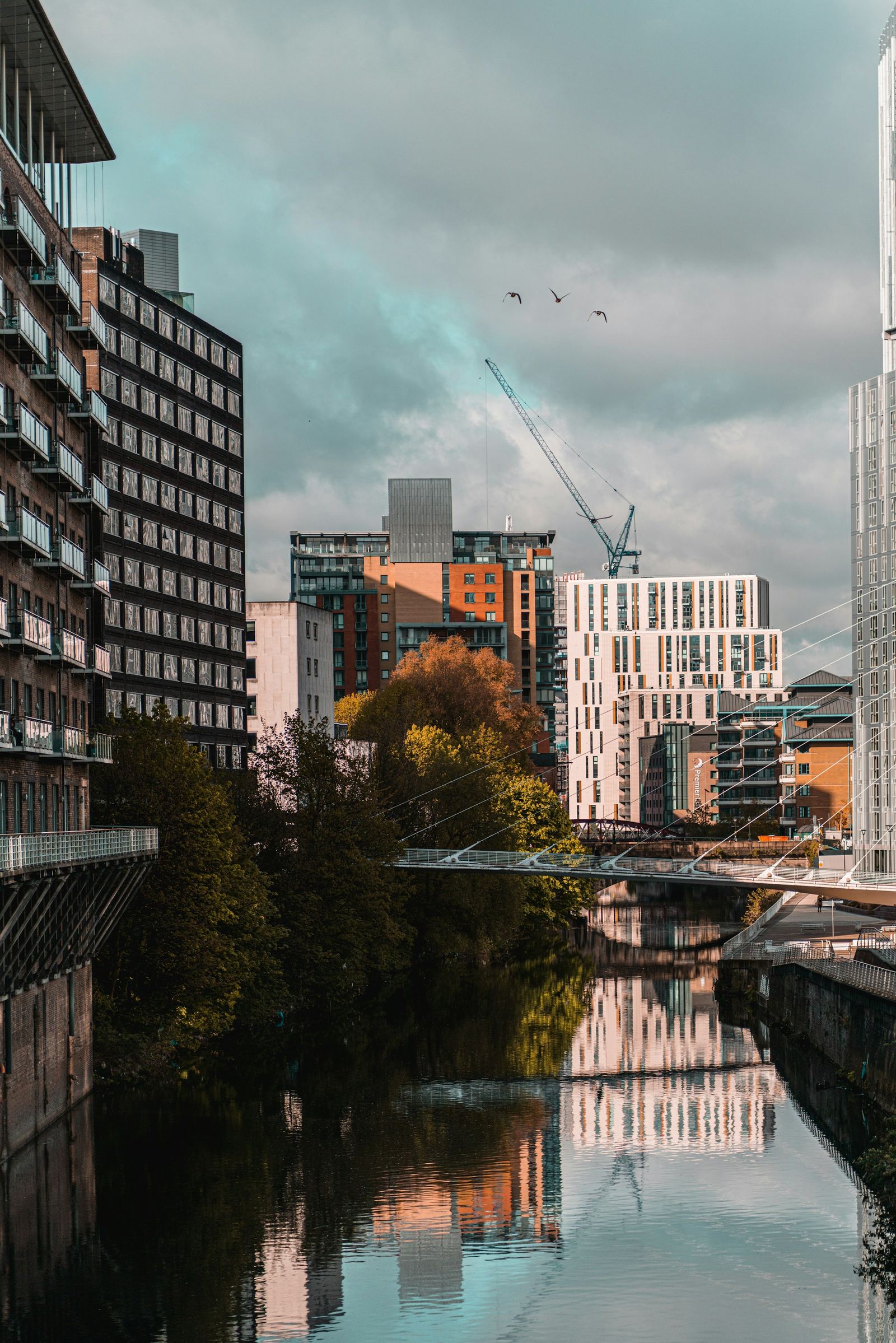 Apartment buildings along a Manchester waterway, with a tower crane rising behind them